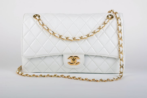 A white Chanel bag with a gold chain and logo.